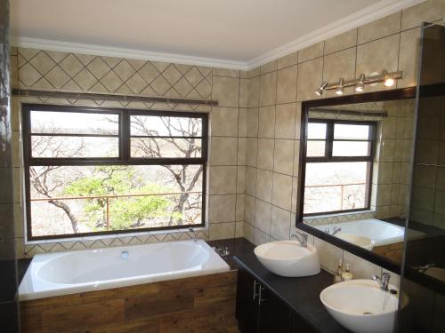 奧喬的住宿－Onduri Lodge，一间带两个盥洗盆和浴缸的浴室以及两个窗户。