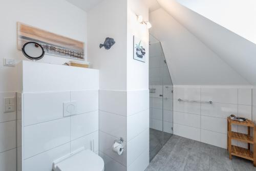 a white bathroom with a shower and a toilet at Haus Passat - Ferienwohnungen in Ostseebad Nienhagen
