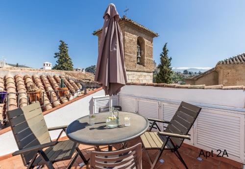 a patio table with an umbrella on a balcony at San José Apartments in Granada