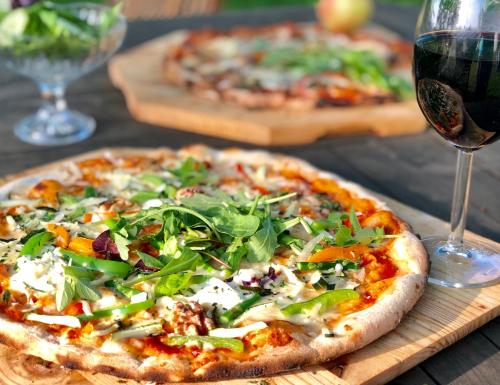 two pizzas sitting on a table with a glass of wine at Tryde 1303 B&B på Österlen in Tomelilla