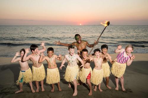 a group of children standing on the beach with a man holding a torch at Radisson Blu Resort Fiji in Denarau