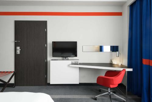 a bedroom with a desk and a red chair at Park Inn by Radisson Hotel Astana in Astana