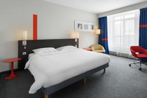 a bedroom with a large white bed and a red chair at Park Inn by Radisson Hotel Astana in Astana