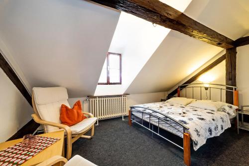 a attic bedroom with a bed and a chair at Penzion Landauer in Český Krumlov