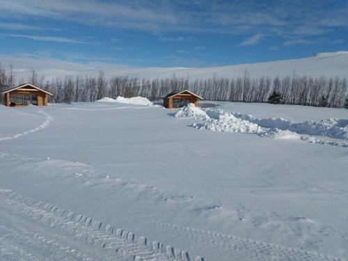a field covered in snow with houses in the background at Miðhvammur Farm Stay in Aðaldalur