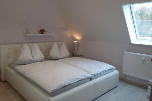 a white bed with white pillows in a bedroom at Ferienwohnung Meeresbrise in Aventoft