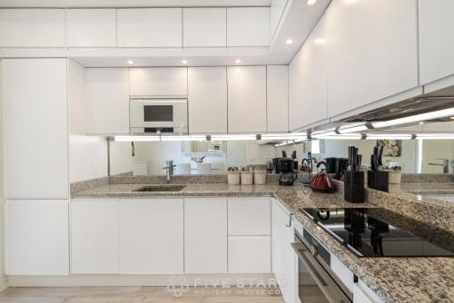 a kitchen with white cabinets and granite counter tops at Suite Versailles Five Stars Holiday House in Nice