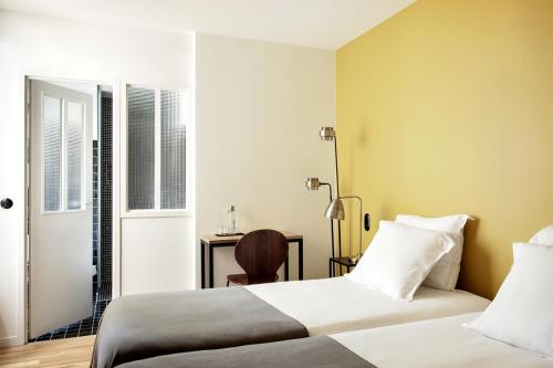 a hotel room with two beds and a desk at New Hotel Le Voltaire in Paris