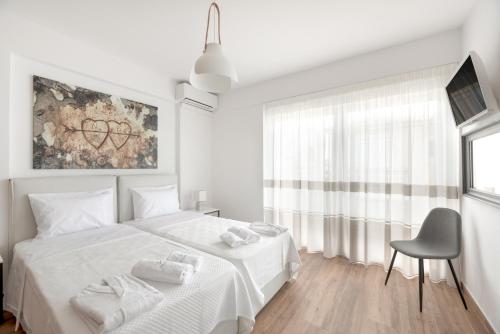 a white bedroom with a white bed and a chair at COSTA VASIA Seaside Suites and Apartments in Vrahati