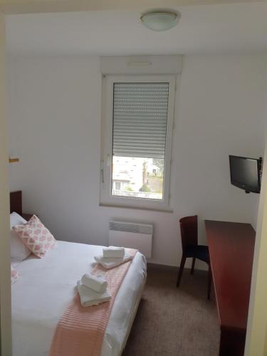 a bedroom with a bed and a window and a desk at Hôtel du Parc in Salies-du-Salat