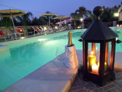 a bottle of wine and a glass next to a swimming pool at Zia Pia in Locogrande