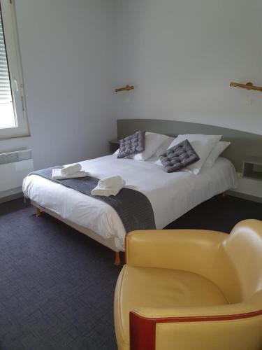 a bedroom with a bed and a yellow chair at Hôtel du Parc in Salies-du-Salat