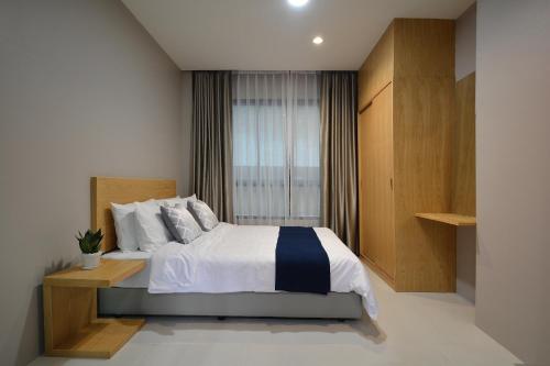 um quarto com uma cama grande e uma janela em The Grey House Palai Phuket em Chalong