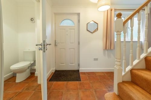 a bathroom with a toilet and a staircase with a door at Waterfront House in Saint Clement