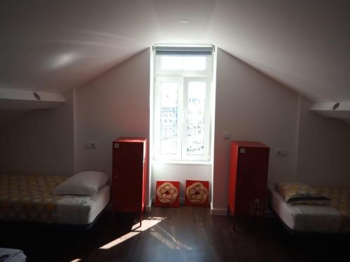 a attic room with two beds and a window at Aveiro Rossio Hostel in Aveiro
