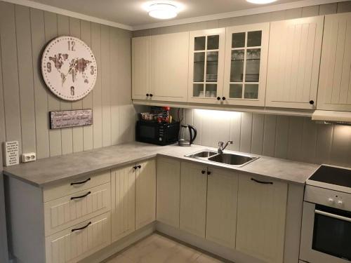 a kitchen with white cabinets and a sink and a clock at Notodden Sentrum Apartment NO 3 in Notodden