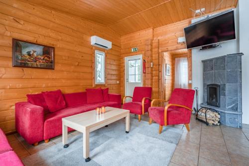 a living room with a red couch and chairs and a tv at Lomaperkkiö Apartments in Vuokatti