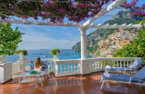 una mujer sentada en un porche con vistas al océano en Villa Boheme Exclusive Luxury Suites en Positano