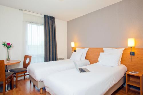ein Hotelzimmer mit 2 Betten und einem Tisch in der Unterkunft Séjours & Affaires Nantes La Beaujoire in Nantes