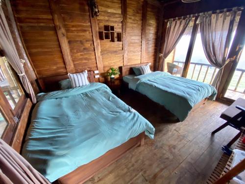 two beds in a room with wooden walls and windows at Pu Luong Ecocharm in Hương Bá Thước