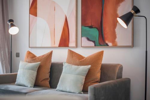 ein Wohnzimmer mit einem Sofa mit Kissen und Gemälden in der Unterkunft Tu Escapada Urbana - Plaza de Castilla III, Diseño y Localización in Madrid