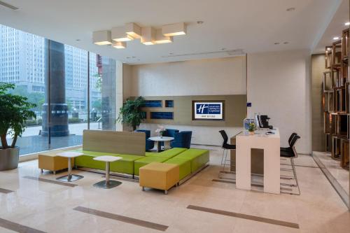 a lobby with a green couch and tables and chairs at Holiday Inn Express Luoyang City Center by IHG in Luoyang
