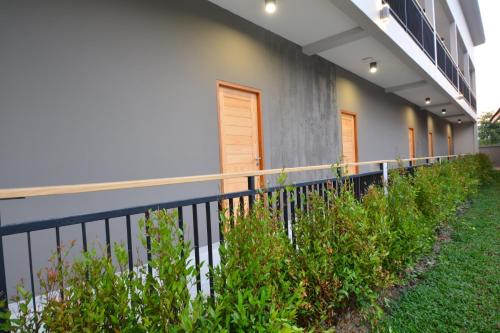 a fence in front of a building with plants at The Grey House Palai Phuket in Chalong 
