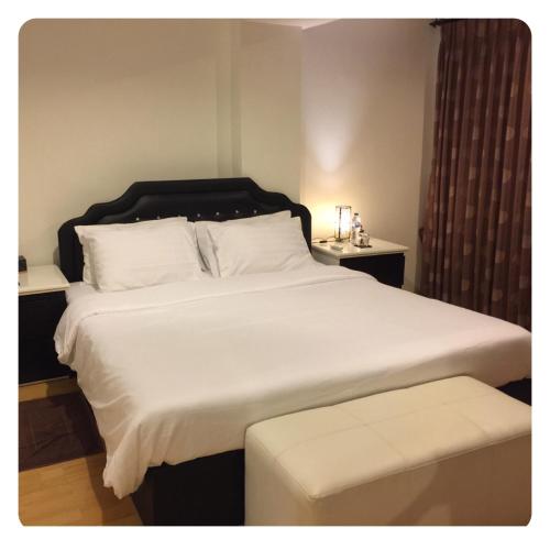 a bedroom with a large white bed and a stool at Apartment in Ranghill Residence Phuket by month in Phuket Town