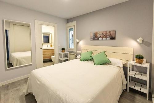 a bedroom with a large white bed with two green pillows at VIVE BURGOS VUT-09 200 in Burgos