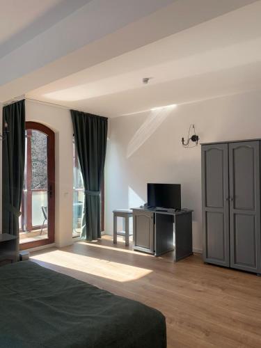 a bedroom with a bed and a tv and a window at Pension Casa Vanatorilor in Băile Olăneşti