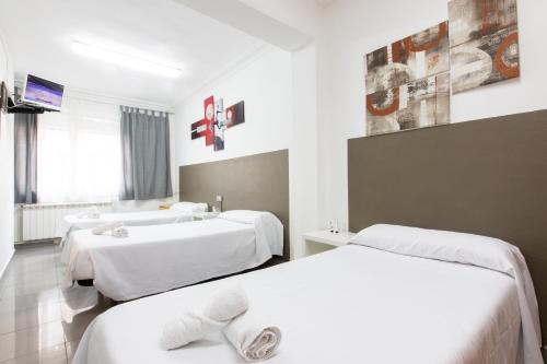 a hotel room with two beds and a bathroom at Pensión Galicia in Canovellas