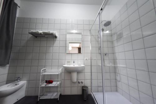 ein weiß gefliestes Bad mit einem Waschbecken und einer Dusche in der Unterkunft Ripahome B&B in Ripalimosani