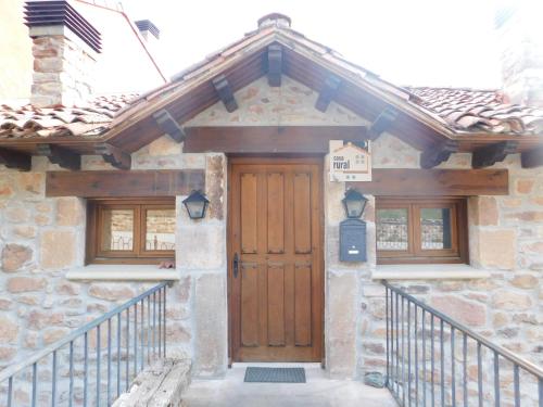 Casa de piedra con puerta de madera y balcón en Las Hoyas I y II en Tolbaños de Arriba