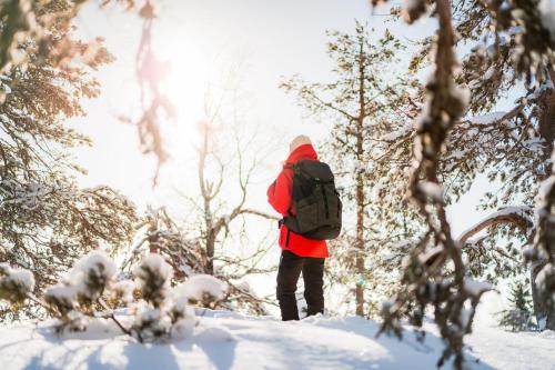 a person with a backpack walking through the snow at Lomaperkkiö Apartments in Vuokatti