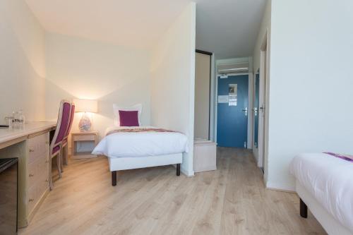 a white room with two beds and a desk and a table at Hôtel Restaurant du Château in Rocamadour