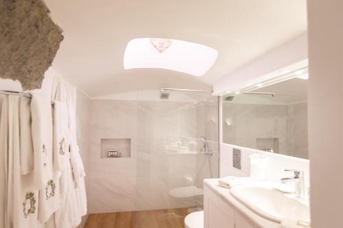 a white bathroom with a shower and a sink at The Tsitouras Collection in Firostefani