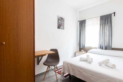 a hotel room with two beds and a desk at Pensión Galicia in Canovellas