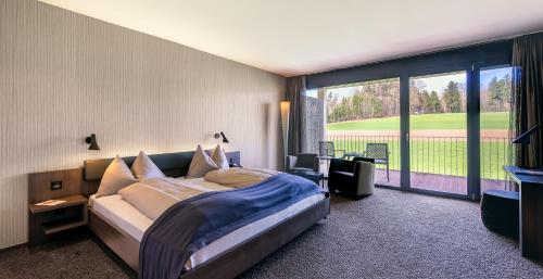 um quarto com uma cama grande e uma janela grande em Wellnesshotel Golf Panorama em Lipperswil