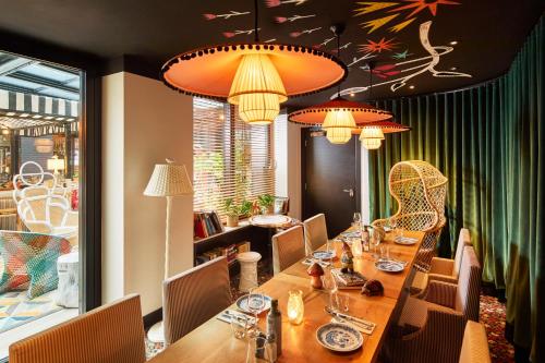 a restaurant with a long table with chairs and lights at Mama Shelter London - Shoreditch in London