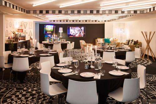 a dining room with tables and white chairs at Mama Shelter London - Shoreditch in London