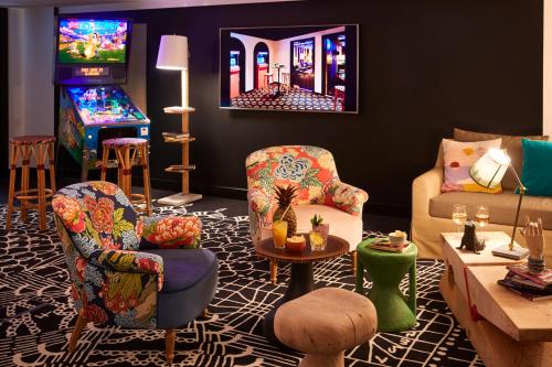 a living room with two chairs and a video game at Mama Shelter London - Shoreditch in London