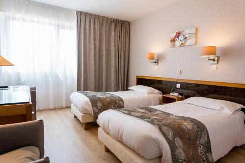 a hotel room with two beds and a window at Hôtel Restaurant du Château in Rocamadour