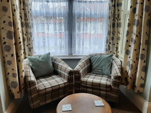 two chairs and a table in a room with windows at Rosemead Guest House in Paignton