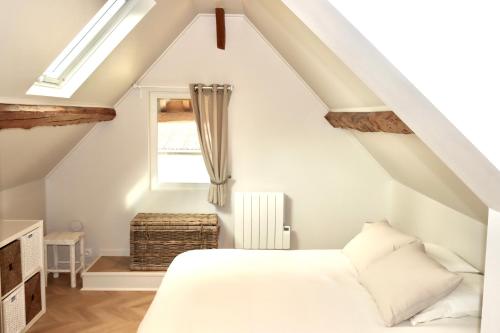 a bedroom with a white bed and a window at Les maisons de Charlotte (2) in Glanville