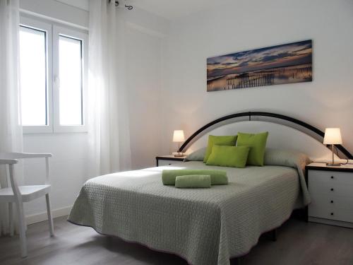 een witte slaapkamer met een bed met groene kussens bij El piso de Ursula in Ayamonte