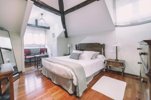 a bedroom with a large white bed and a table at La Casona de Amandi in Villaviciosa