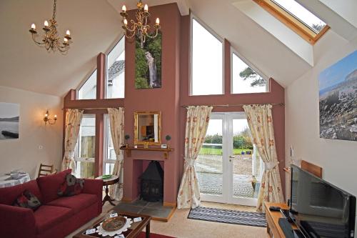 a living room with a fireplace and large windows at Viewbank Cottage in Whiting Bay