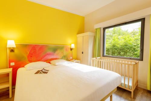 een slaapkamer met een groot wit bed en een raam bij Center Parcs Les Trois Forêts in Hattigny