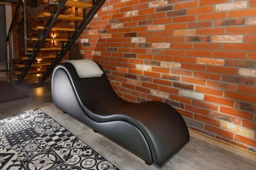a black chair in front of a brick wall at Loft Szpularnia in Żyrardów
