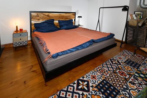 sypialnia z łóżkiem z pomarańczowym kocem i dywanem w obiekcie Loft Szpularnia w mieście Żyrardów